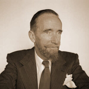 H. F. Heard, circa 1955. Sepia photograph of a man in a suit and tie with short hair and a pointed beard