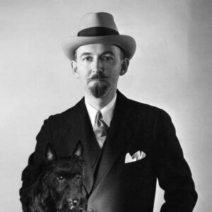 S.S. Van Dine author photo. Black and white photograph of man in a suit and hat holding a black dog.