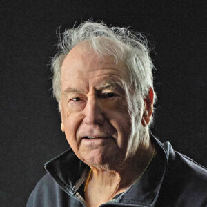 Peter Rowe author photo. Headshot of a man with white hair, wearing a gray collared shirt.