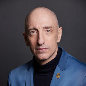 Headshot of Jim Clemente, a bald man in a blue blazer and black shirt.